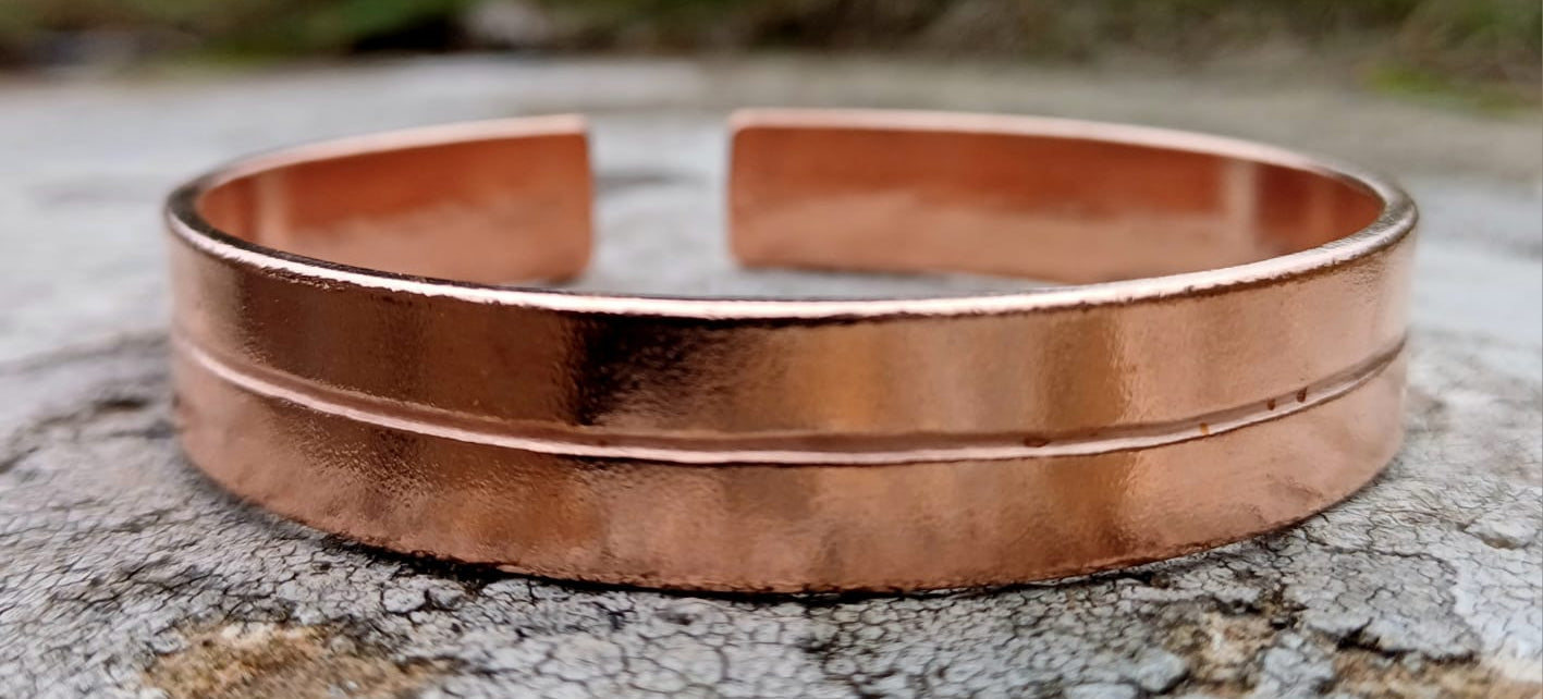 Copper bracelet on a textured surface with a natural background